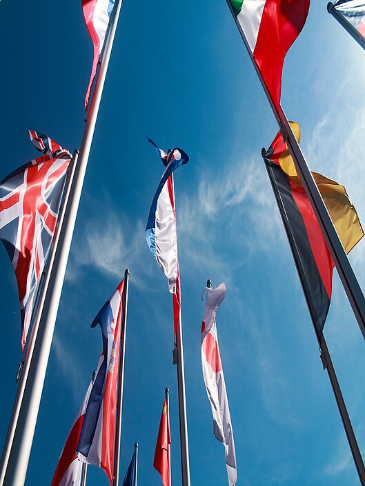 Flaggenmaste mit Länderfahnen aus der Froschperspektive fotografiert